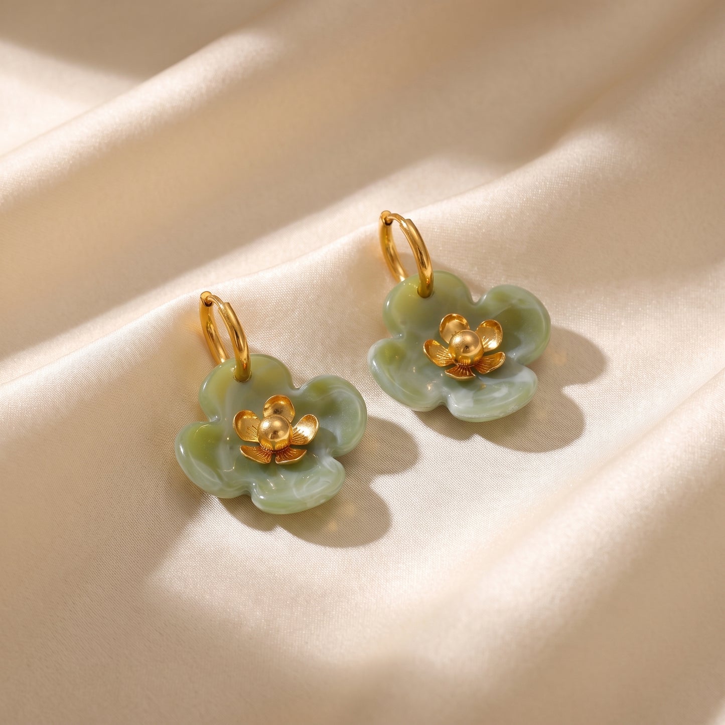 The high quality Fleur Resin Drop Hoops in Sage Green by Floravisha, featuring marbled green resin and gold-plated flower centers on a clean white background.