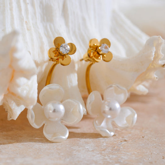 Gold and pearl flower-shaped earrings on a textured white surface. latest earring models and trending earrings models. new arrivals.