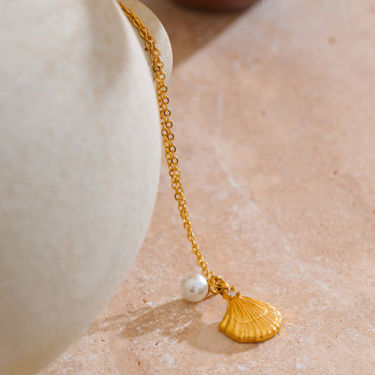 Gold bracelet with a shell charm.