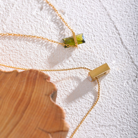 Gold necklace with a green gemstone pendant.