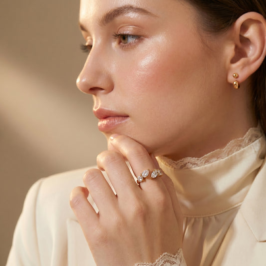 Close-up of a woman wearing Aurora Crystal Cluster Adjustable Ring by Floravisha. A high-quality, waterproof gold-plated open wrap ring featuring an elegant, asymmetrical botanical cluster of teardrop and round clear crystals. Tarnish-free and skin-friendly.