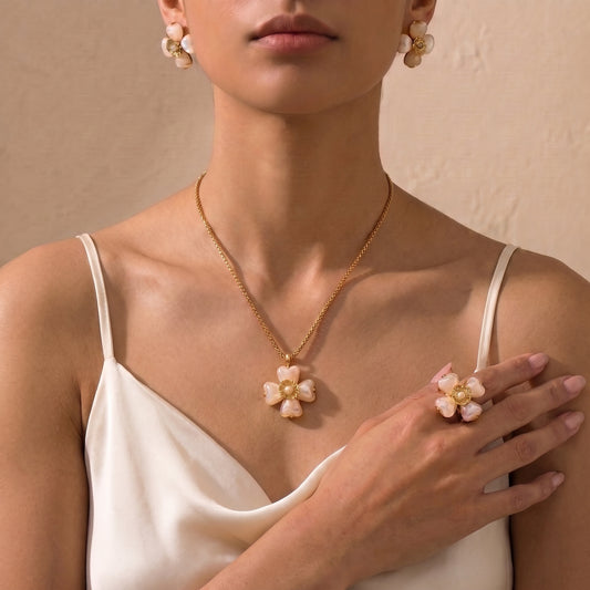 A close-up of a model wearing a high quality Fleur Bloom Pendant Necklace in Cream Alabaster by Floravisha, showing the marbled resin flower pendant and gold box chain, matching earrings and ring.