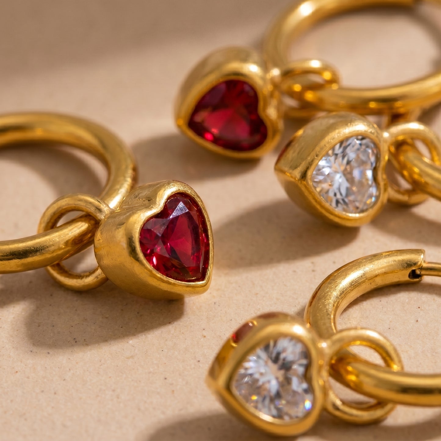 High quality waterproof gold plated huggie hoop earrings featuring sparkling ruby red and clear crystal heart dangle charms, displayed on a clean background