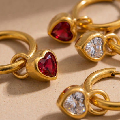 High quality waterproof gold plated huggie hoop earrings featuring sparkling ruby red and clear crystal heart dangle charms, displayed on a clean background