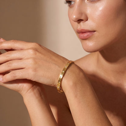 women wearing a Sleek gold Aria Bangle featuring channel-set clear baguette crystals on a clean background, highlighting its tarnish-free and skin friendly finish.