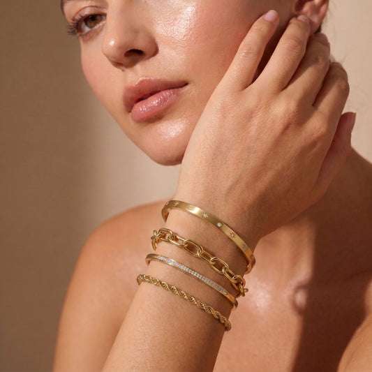 women wearing a Sleek gold Aria Bangle featuring channel-set clear baguette crystals on a clean background, highlighting its tarnish-free and skin friendly finish.