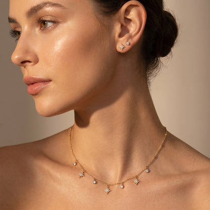 Dainty gold chain necklace featuring alternating dangling starburst charms and clear crystal drops on a clean white background, highlighting its tarnish-free and skin friendly finish.