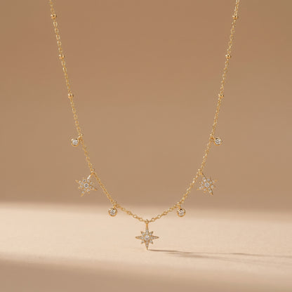 Dainty gold chain necklace featuring alternating dangling starburst charms and clear crystal drops on a clean background, highlighting its tarnish-free and skin friendly finish.