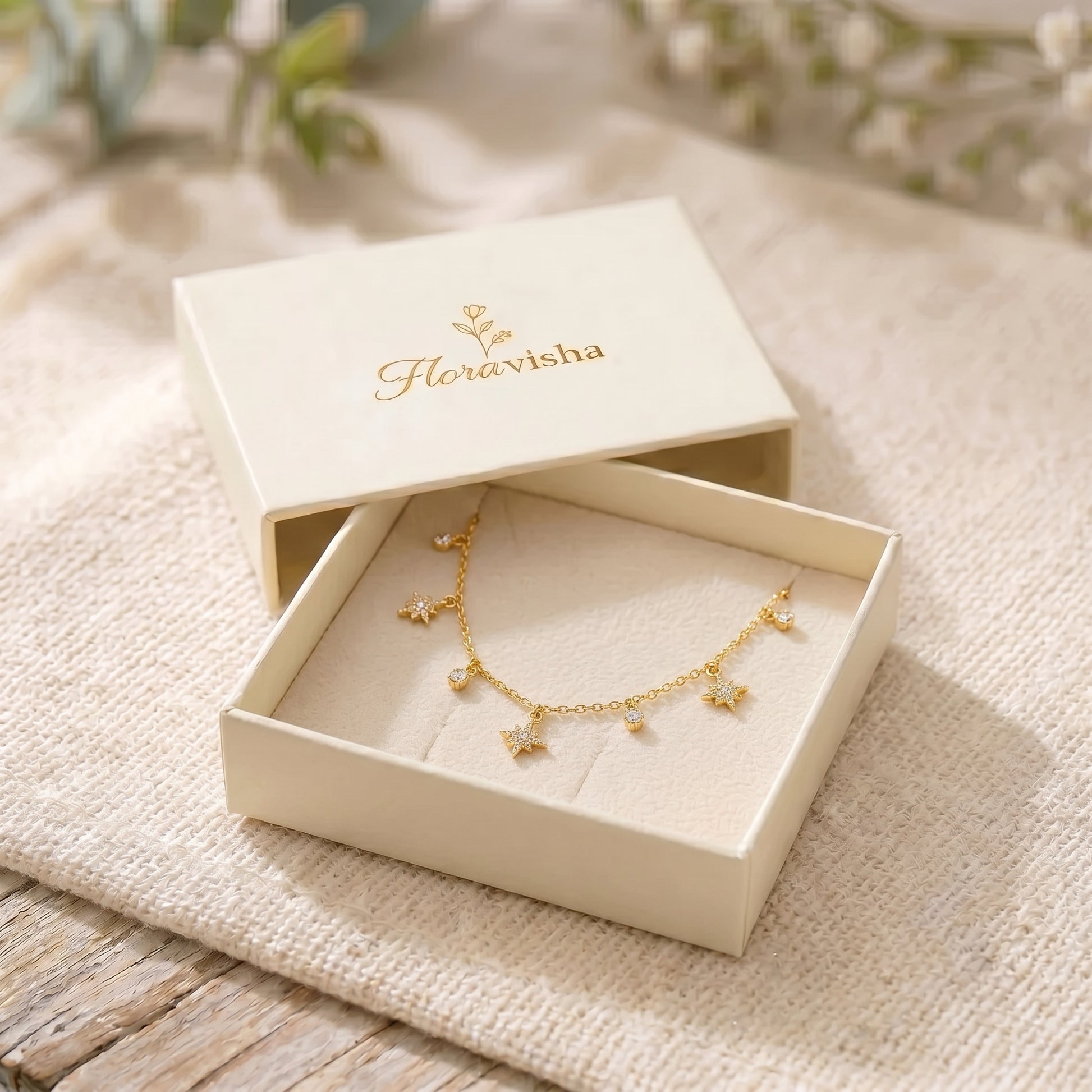 Dainty gold chain necklace featuring alternating dangling starburst charms and clear crystal drops on a clean background, highlighting its tarnish-free and skin friendly finish.