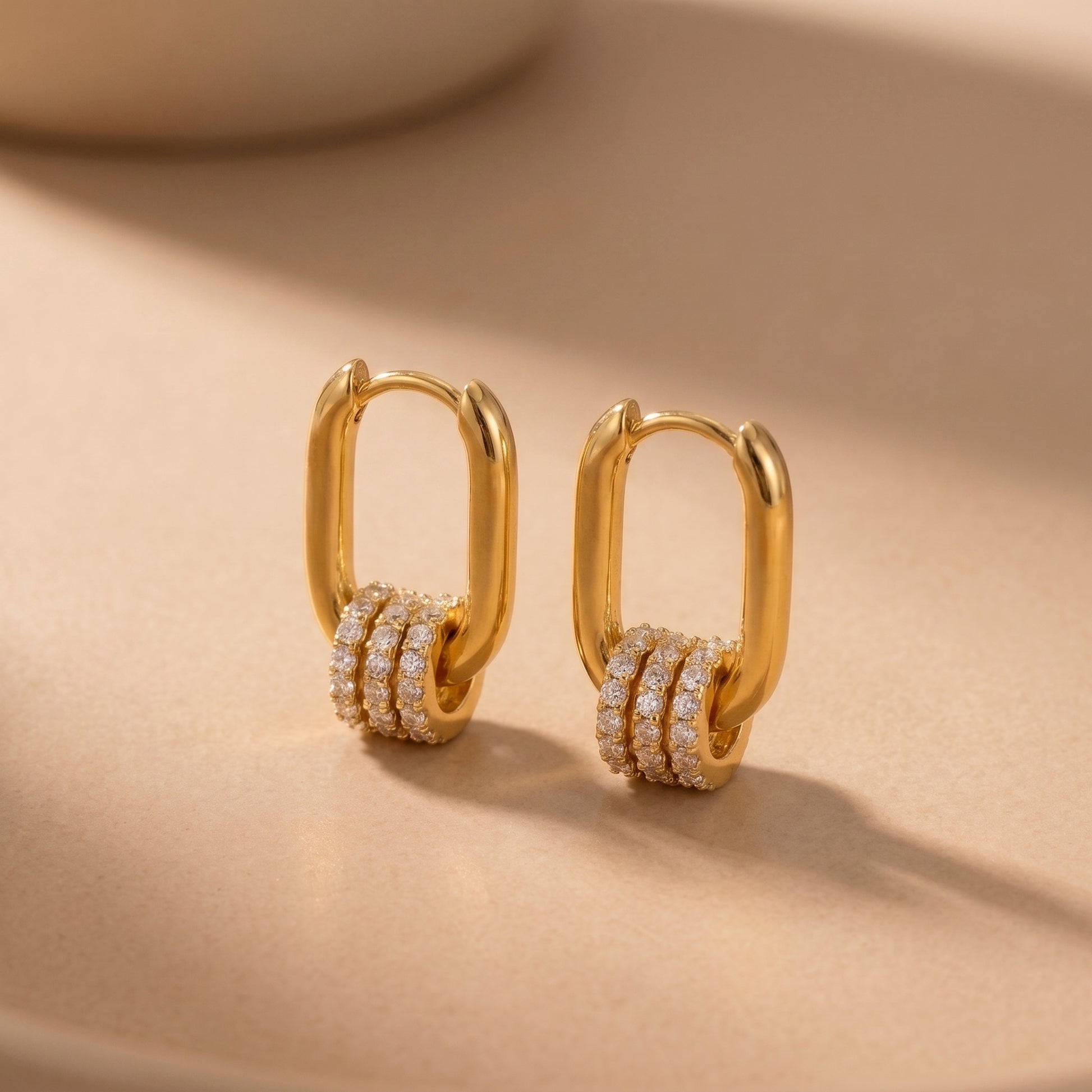 The tarnish-free gold Aurelia Eternity Hoops showing a pair of elongated rectangular huggies with three sliding crystal pavé charms