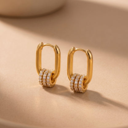 The tarnish-free gold Aurelia Eternity Hoops showing a pair of elongated rectangular huggies with three sliding crystal pavé charms