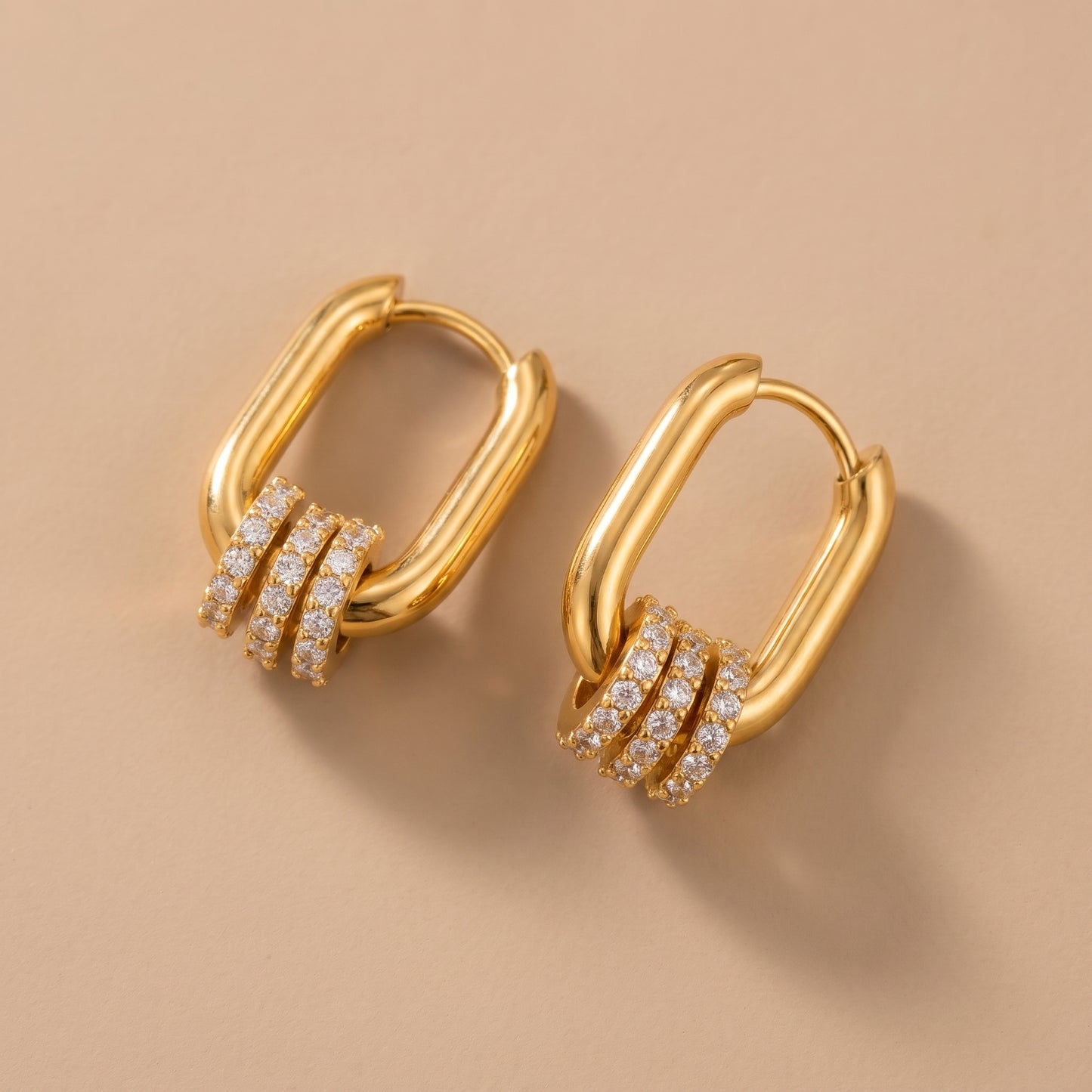 The tarnish-free gold Aurelia Eternity Hoops showing a pair of elongated rectangular huggies with three sliding crystal pavé charms