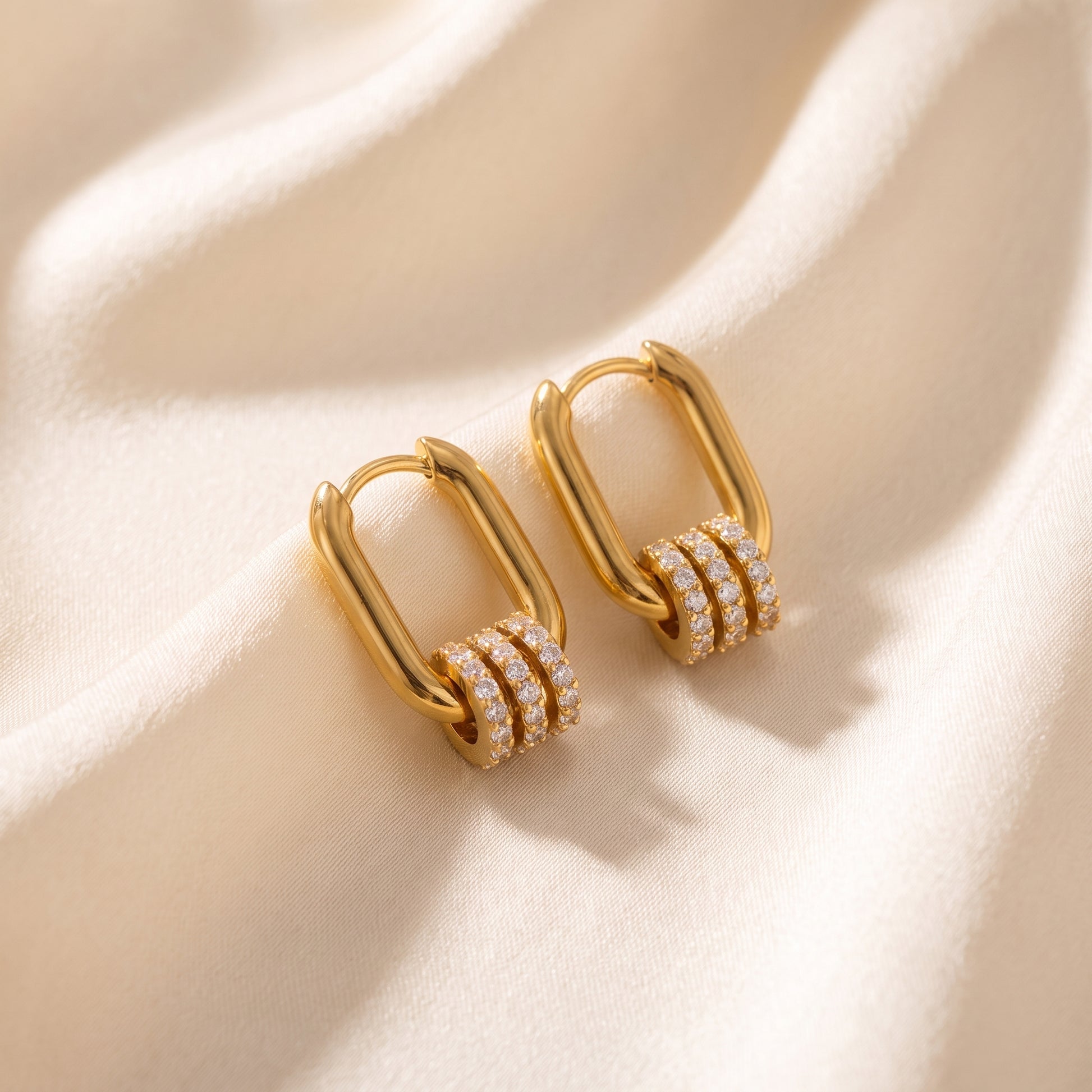 The tarnish-free gold Aurelia Eternity Hoops showing a pair of elongated rectangular huggies with three sliding crystal pavé charms