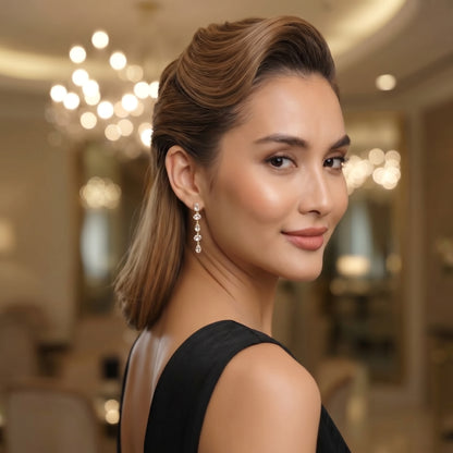Woman in a black dress with elegant earrings in an indoor setting