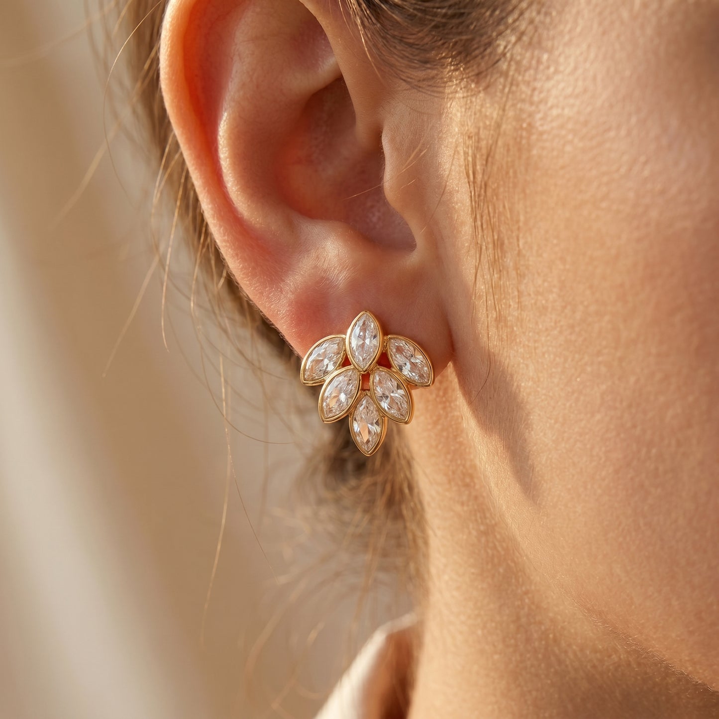 Close-up of a person wearing a High quality waterproof gold plated stud earrings featuring a modern fan design with clear marquise-cut crystals.