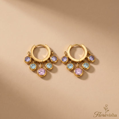 Floravisha multi-color crystal dangle hoop earrings in real gold plating on a tan background.