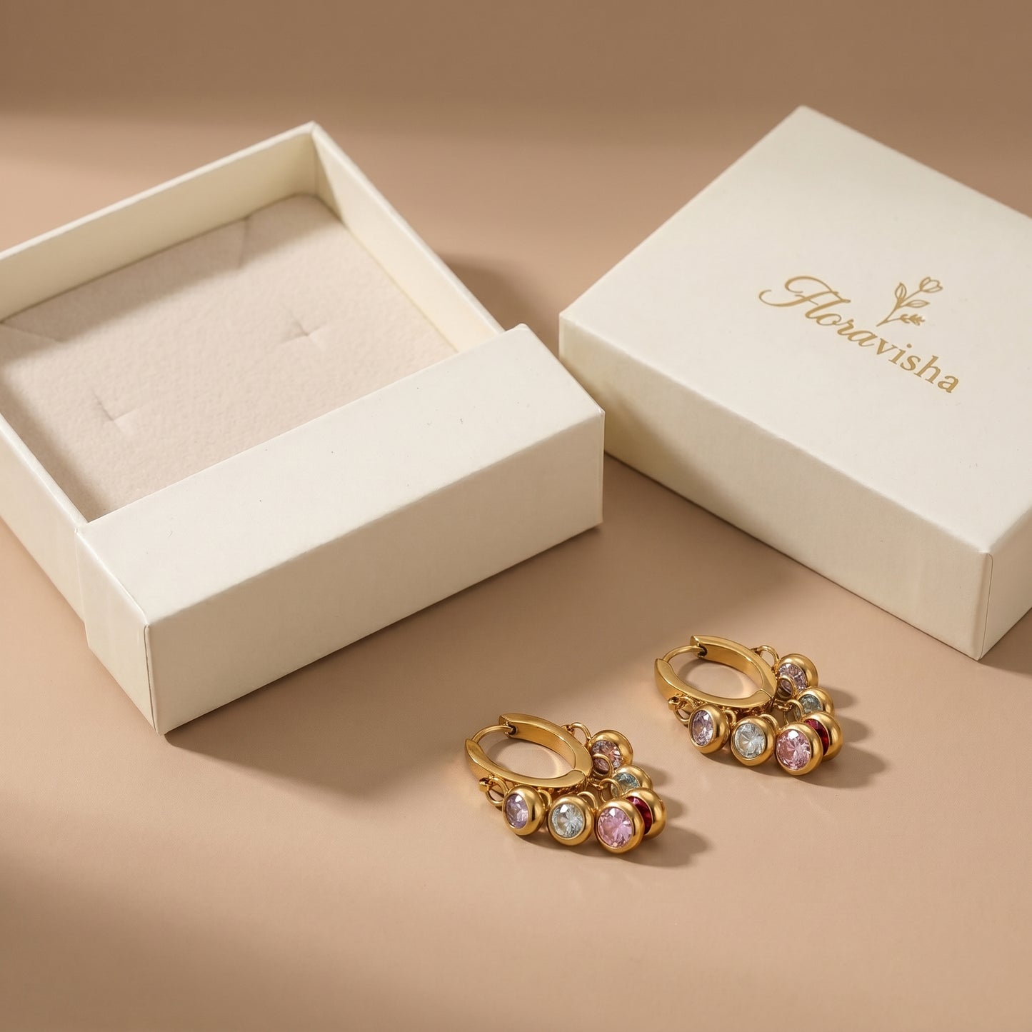 Floravisha jewelry packaging with colorful gemstone gold hoops next to a luxury cream box.
