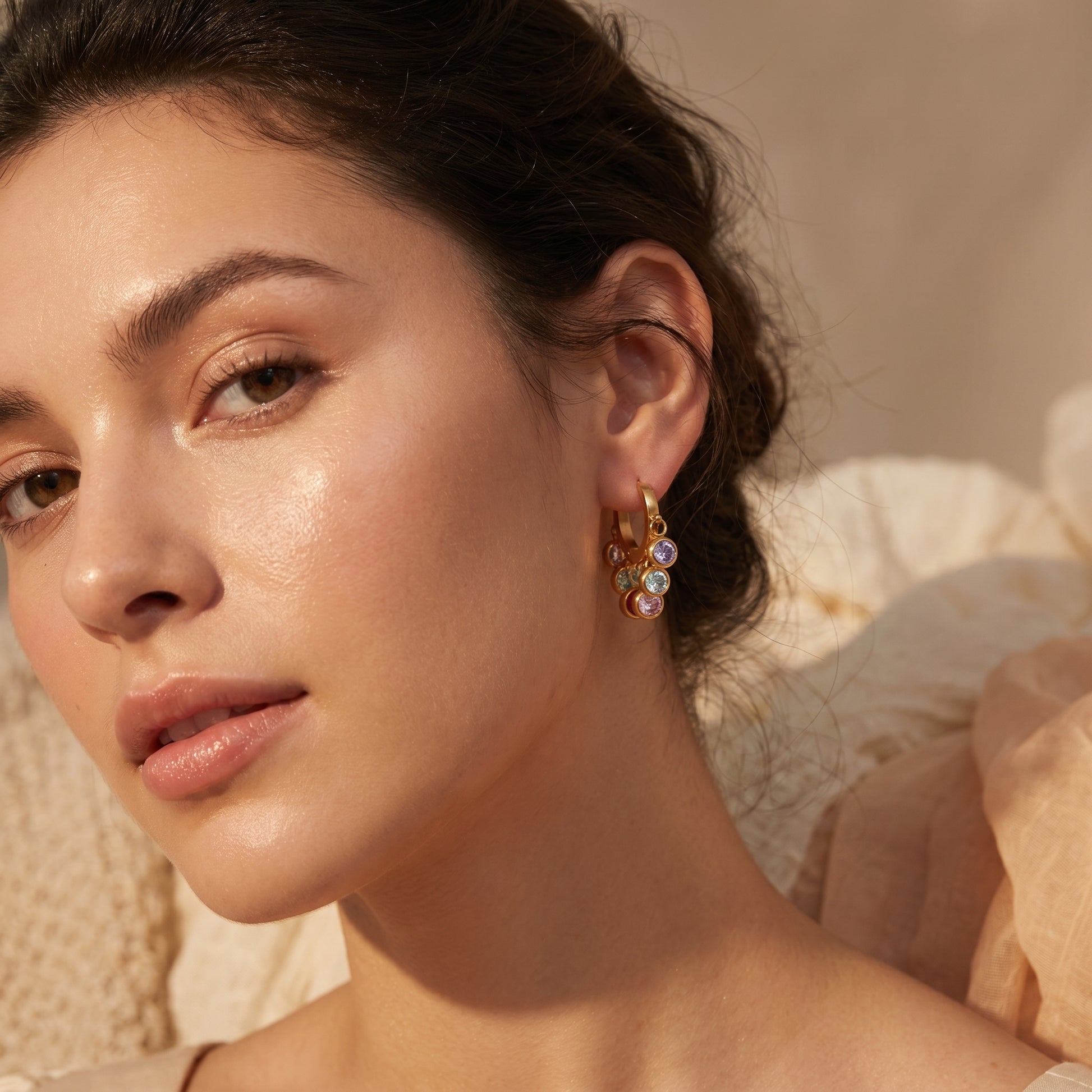 Close-up of a woman wearing Gold multi-color crystal earrings with a neutral background
