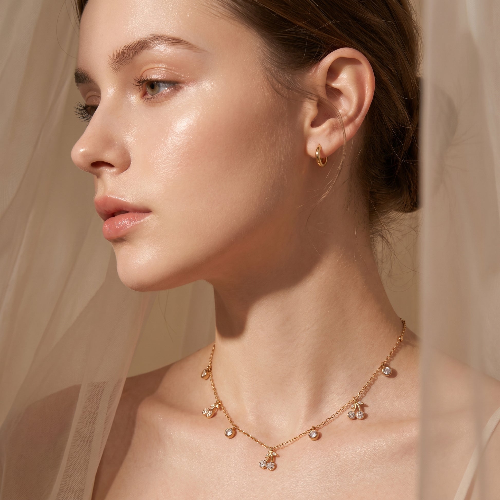Close-up of a woman wearing Elegant dainty gold necklace featuring alternating bezel-set crystals and micro-pave cherry charms against a neutral background.