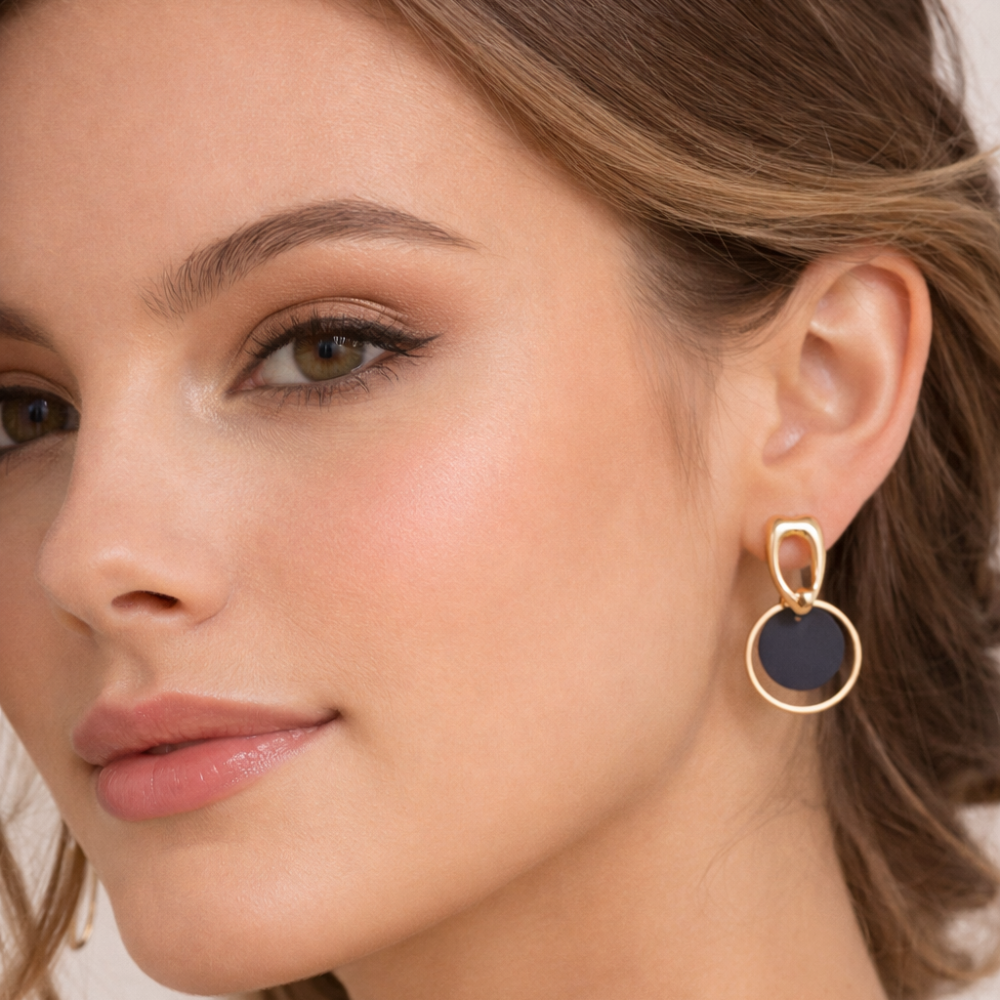 Close-up of a woman wearing a gold and black earring. latest earring models and trending earrings models. new arrivals.