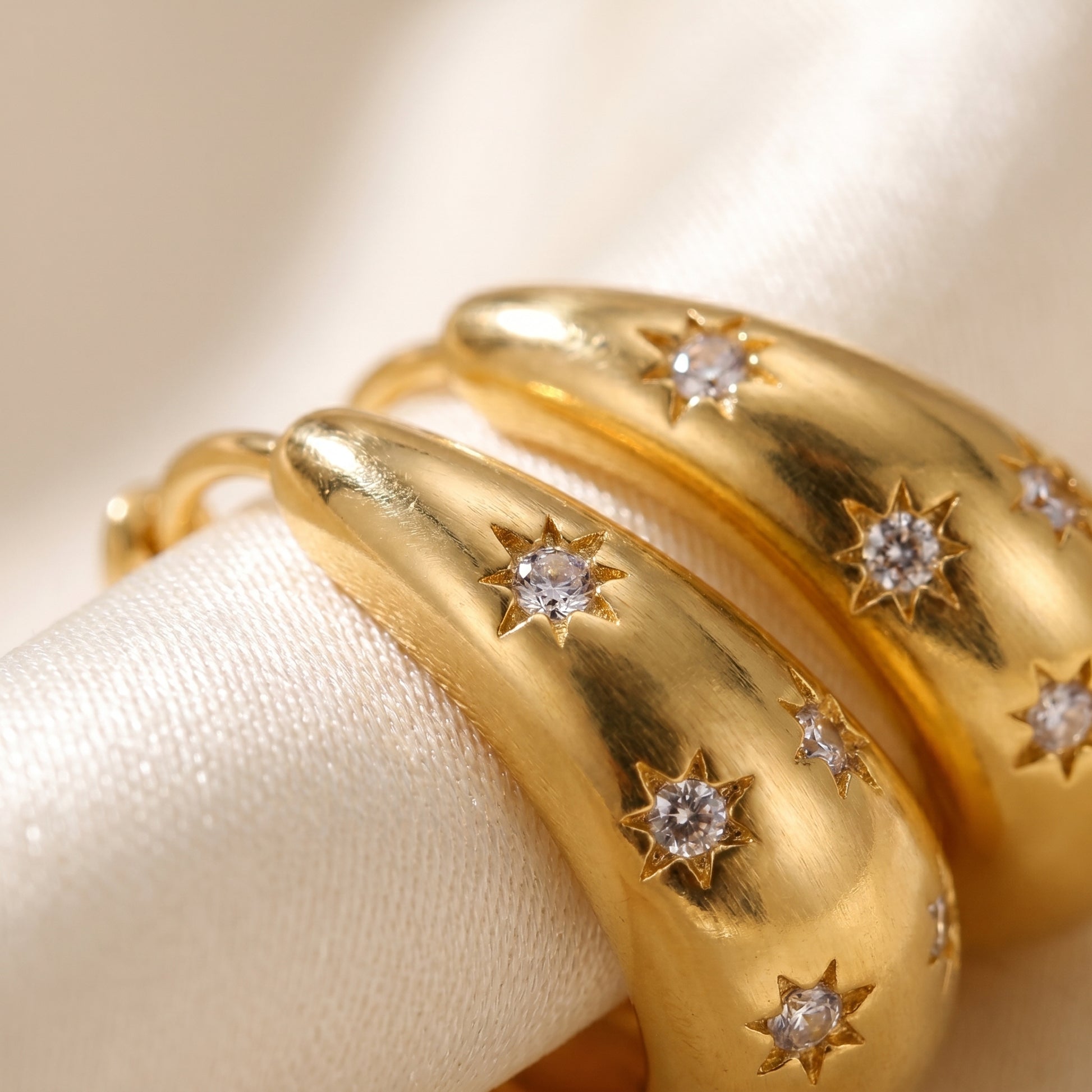 High quality waterproof gold plated chunky dome hoop earrings with engraved starburst crystals, shown standing with a soft reflection on a clean background.