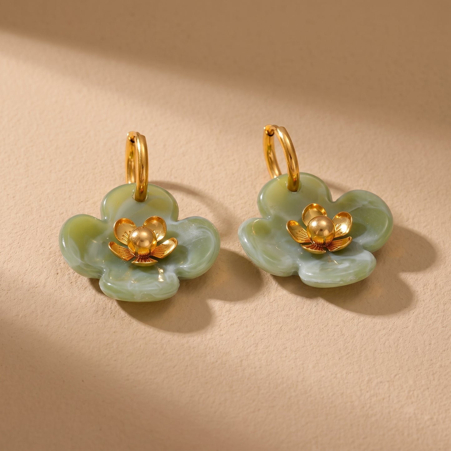 The high quality Fleur Resin Drop Hoops in Sage Green by Floravisha, featuring marbled green resin and gold-plated flower centers on a clean background.