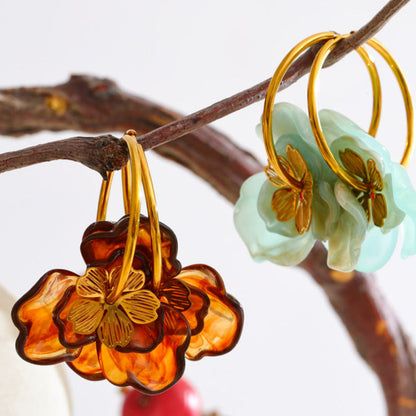 Floral earrings in gold and green on a branch with a blurred background. latest earring models and trending earrings models. new arrivals.