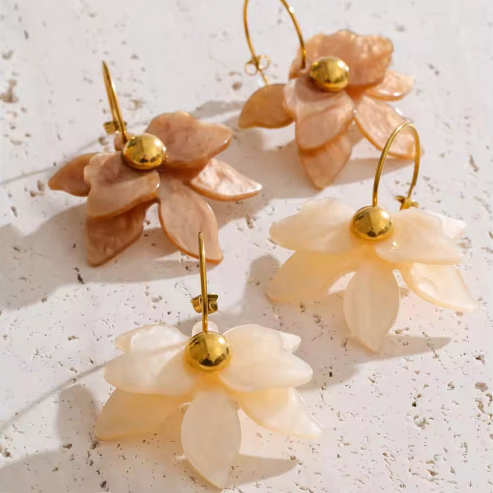 Floral earrings with gold centers on a textured white surface. latest earring models and trending earrings models. new arrivals.