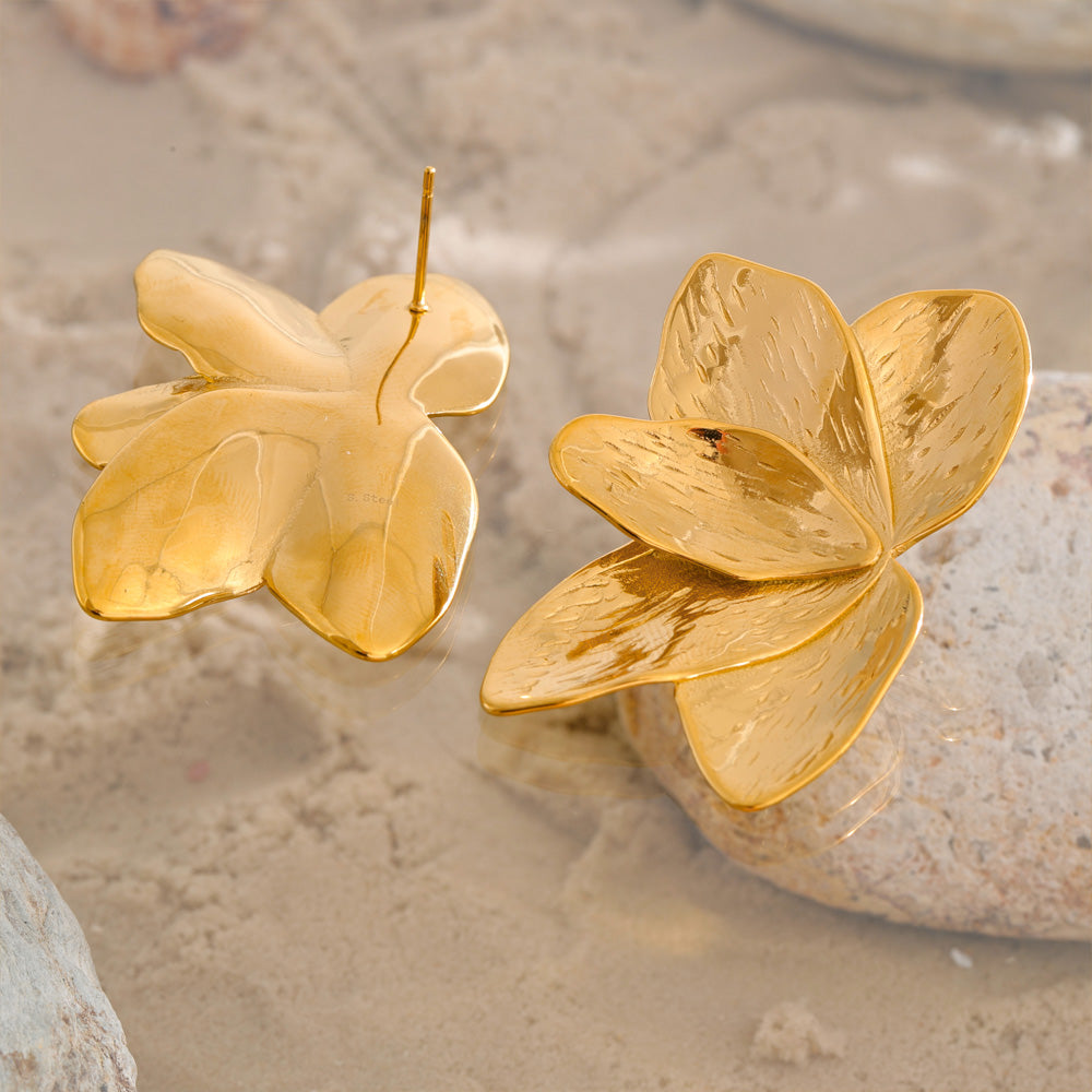 Gold flower-shaped earrings on a sandy background. latest earring models and trending earrings models. new arrivals.