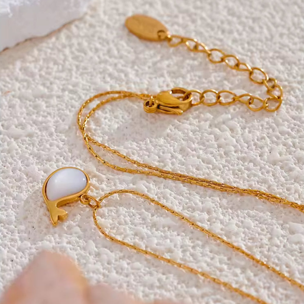 Gold necklace with a white pendant.