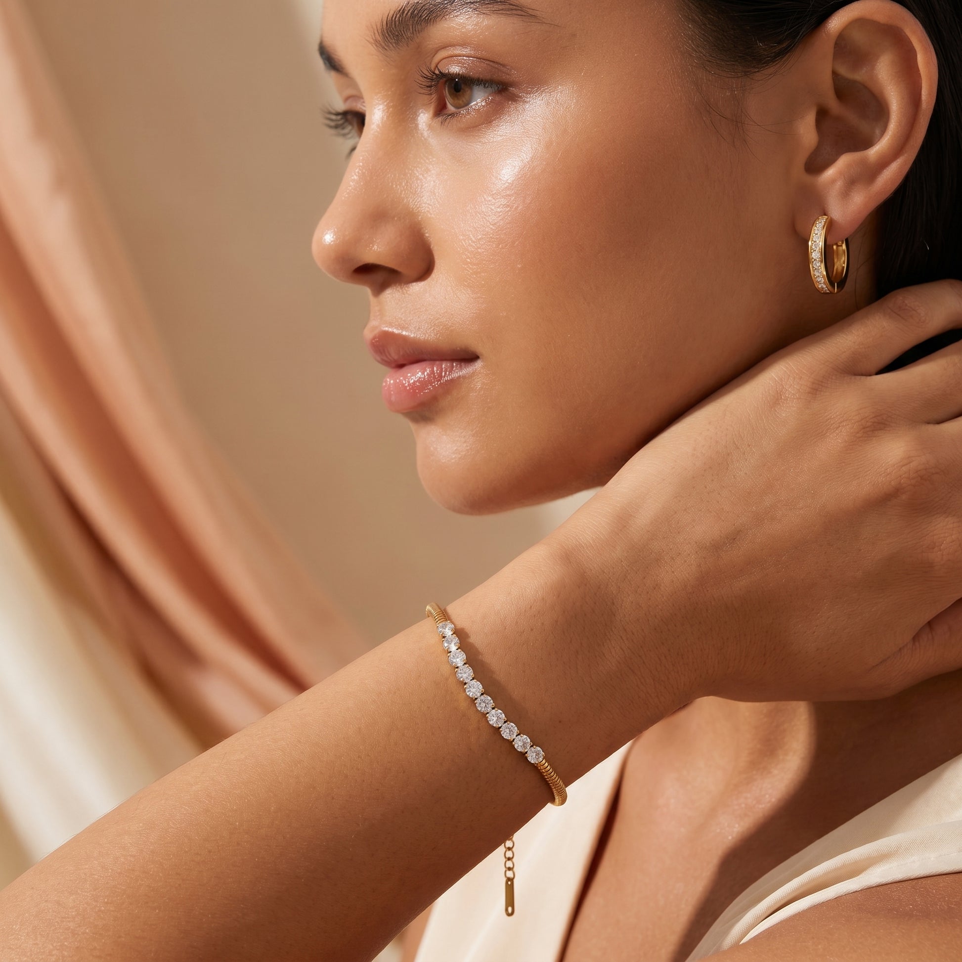 Woman wearingHigh quality waterproof gold plated snake chain bracelet featuring a row of clear crystals against a neutral background.