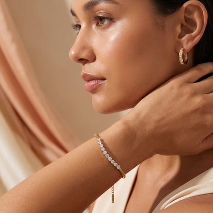 Woman wearingHigh quality waterproof gold plated snake chain bracelet featuring a row of clear crystals against a neutral background.