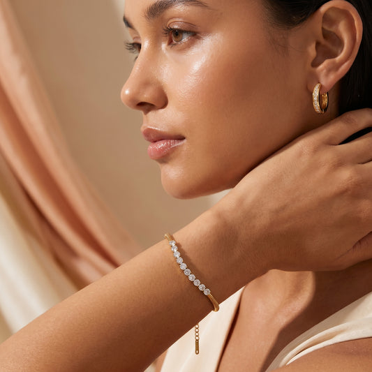 Woman wearingHigh quality waterproof gold plated snake chain bracelet featuring a row of clear crystals against a neutral background.