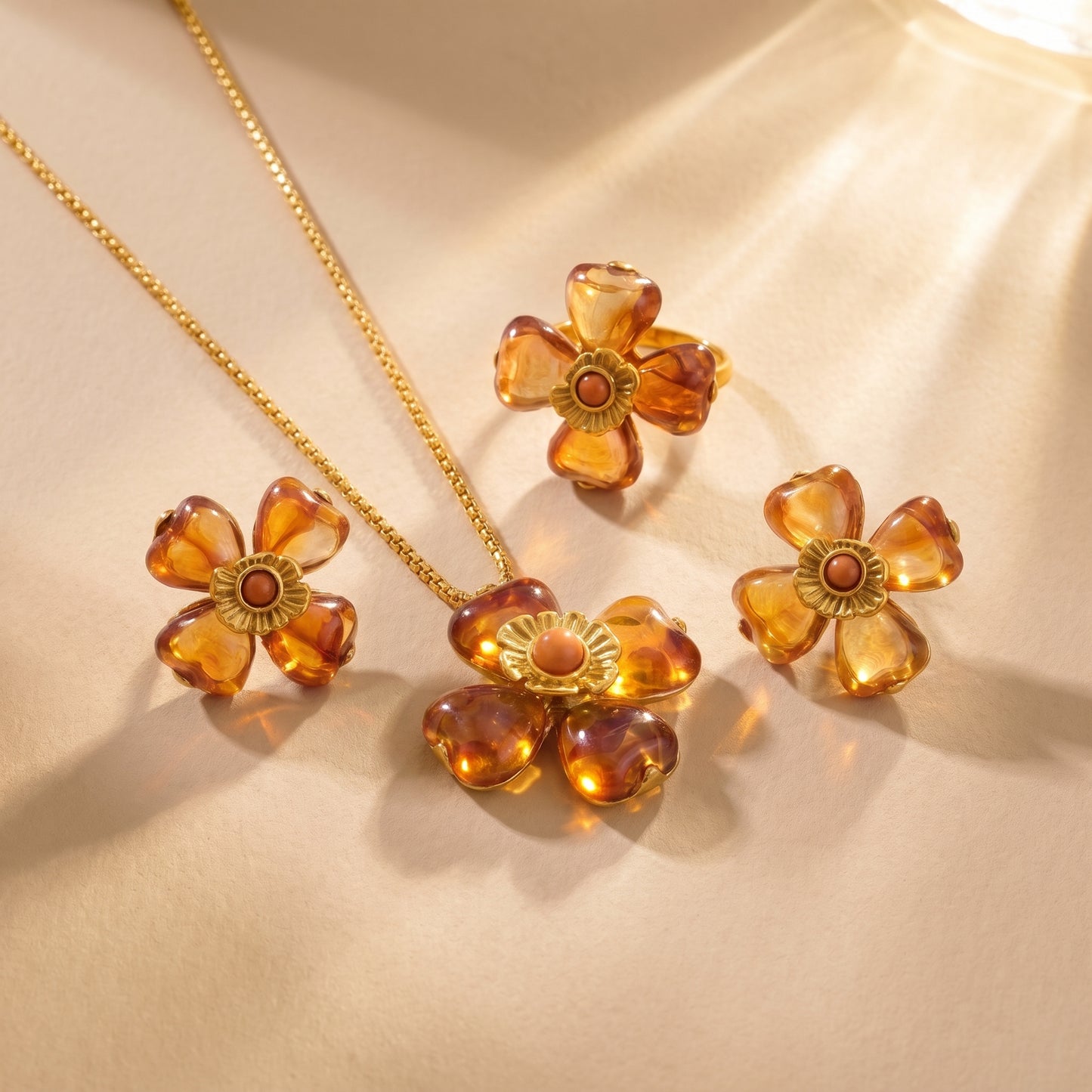 The high quality Fleur Bloom Pendant Necklace in Warm Amber by Floravisha, showing the marbled resin flower pendant and gold box chain next to matching earrings and ring.