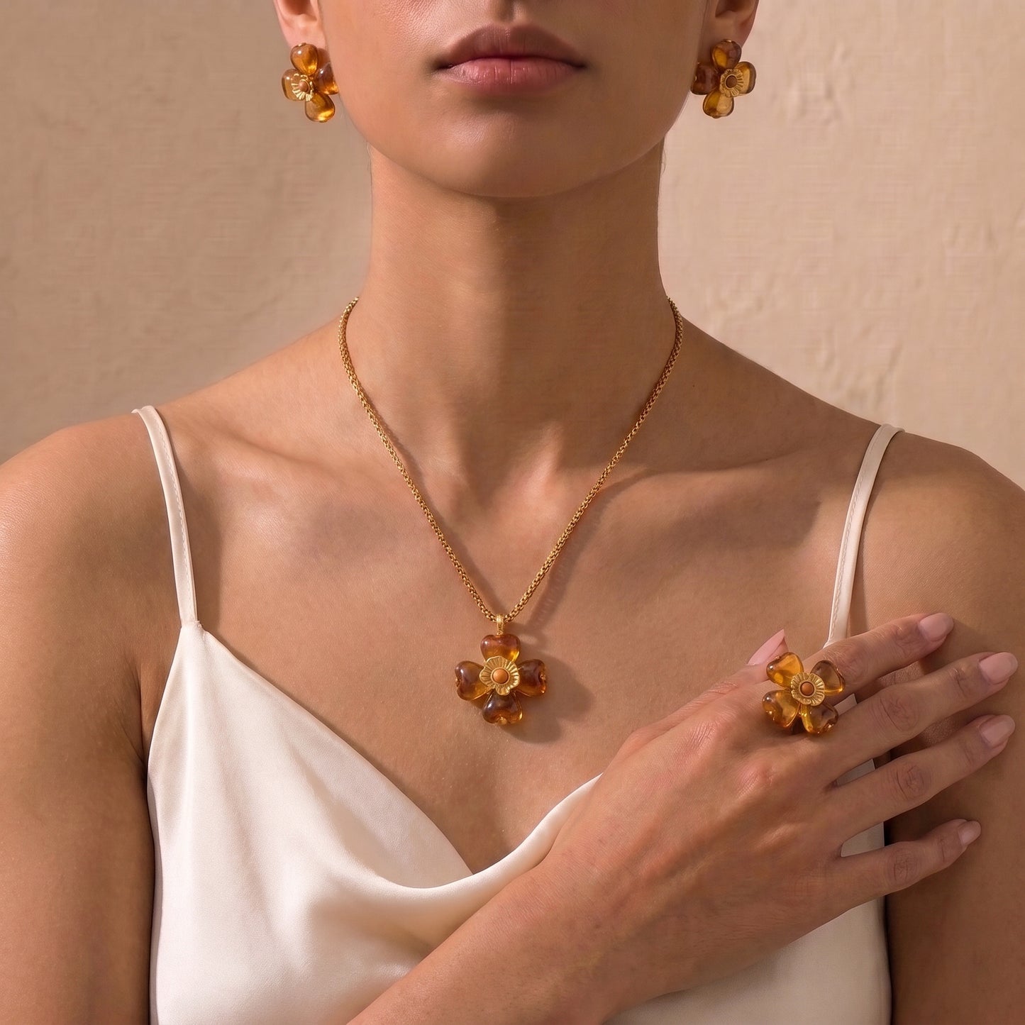 A close-up of a model wearing a high quality Fleur Bloom Pendant Necklace in Warm Amber by Floravisha, showing the marbled resin flower pendant and gold box chain, matching earrings and ring.