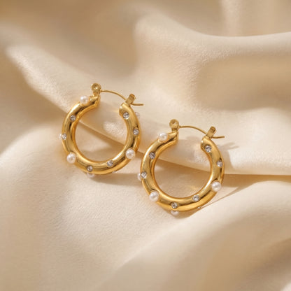 High quality waterproof gold plated chunky hoop earrings featuring scattered pearls and inset crystals, laid flat on a pristin background