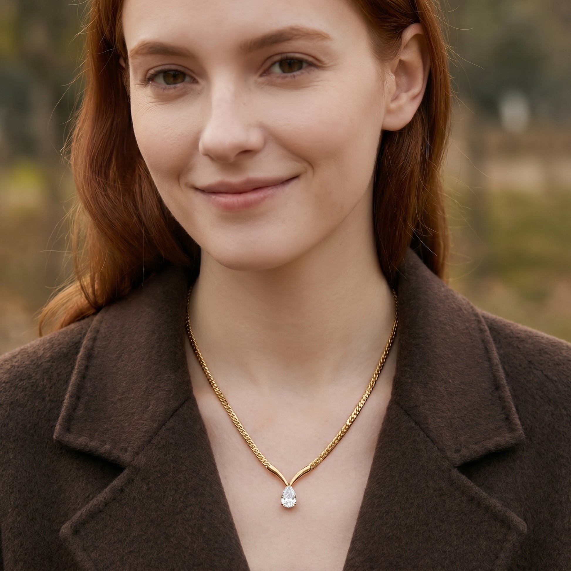 Woman wearing a gold necklace with a diamond pendant outdoors.