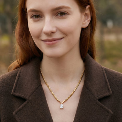 Woman wearing a gold necklace with a diamond pendant outdoors.