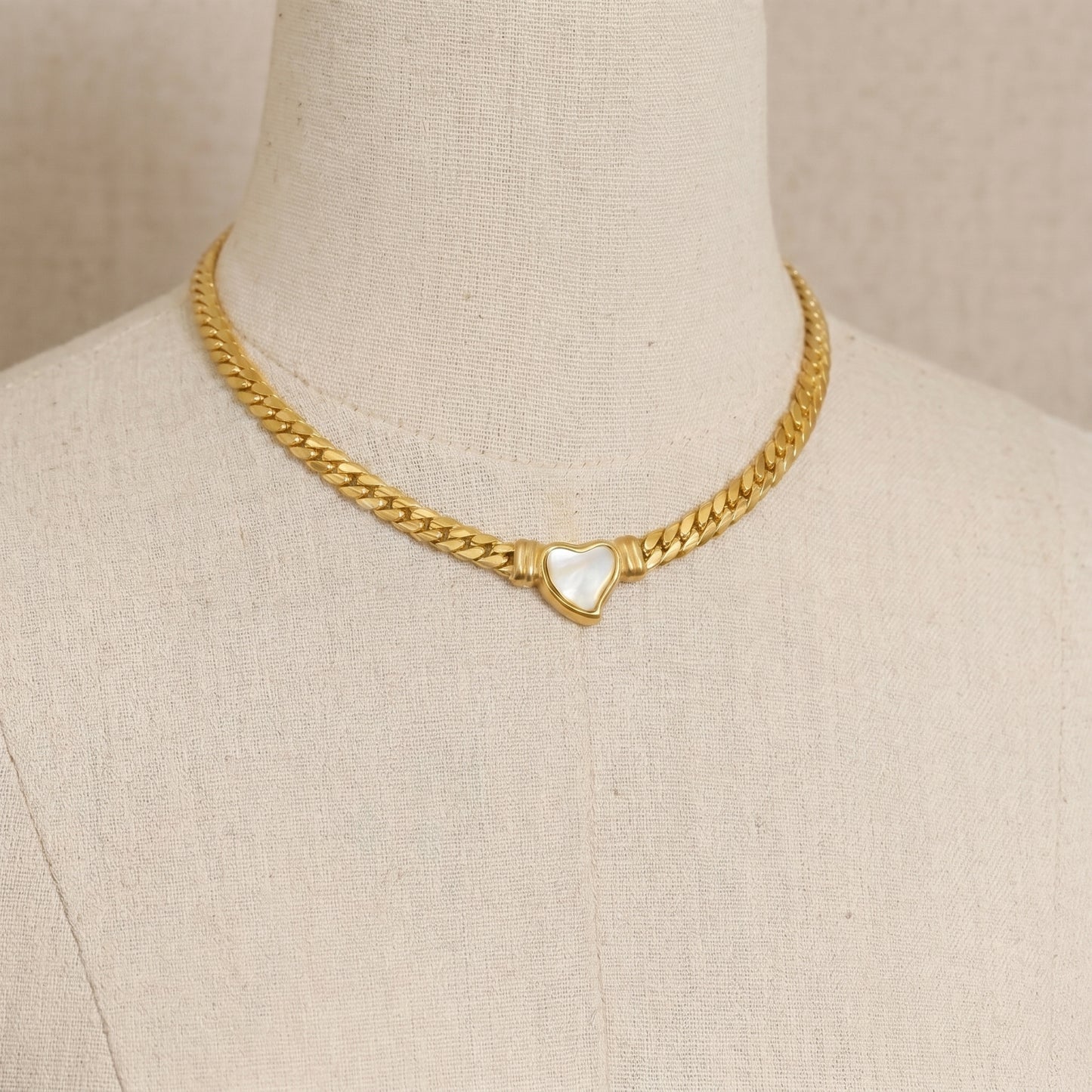 gold snake chain heart pendant necklace on neutral background minimalist luxury jewelry