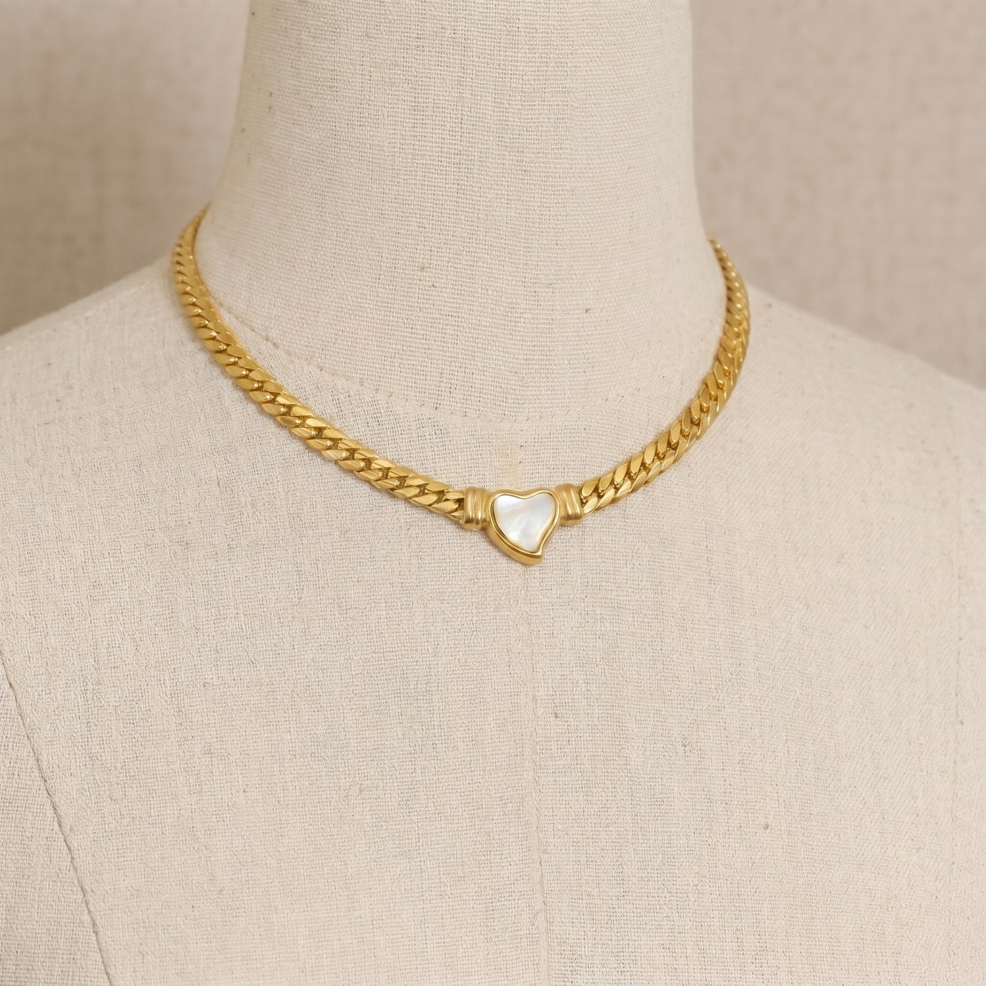 gold snake chain heart pendant necklace on neutral background minimalist luxury jewelry