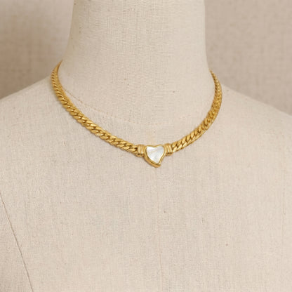 gold snake chain heart pendant necklace on neutral background minimalist luxury jewelry
