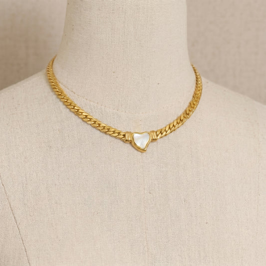 gold snake chain heart pendant necklace on neutral background minimalist luxury jewelry
