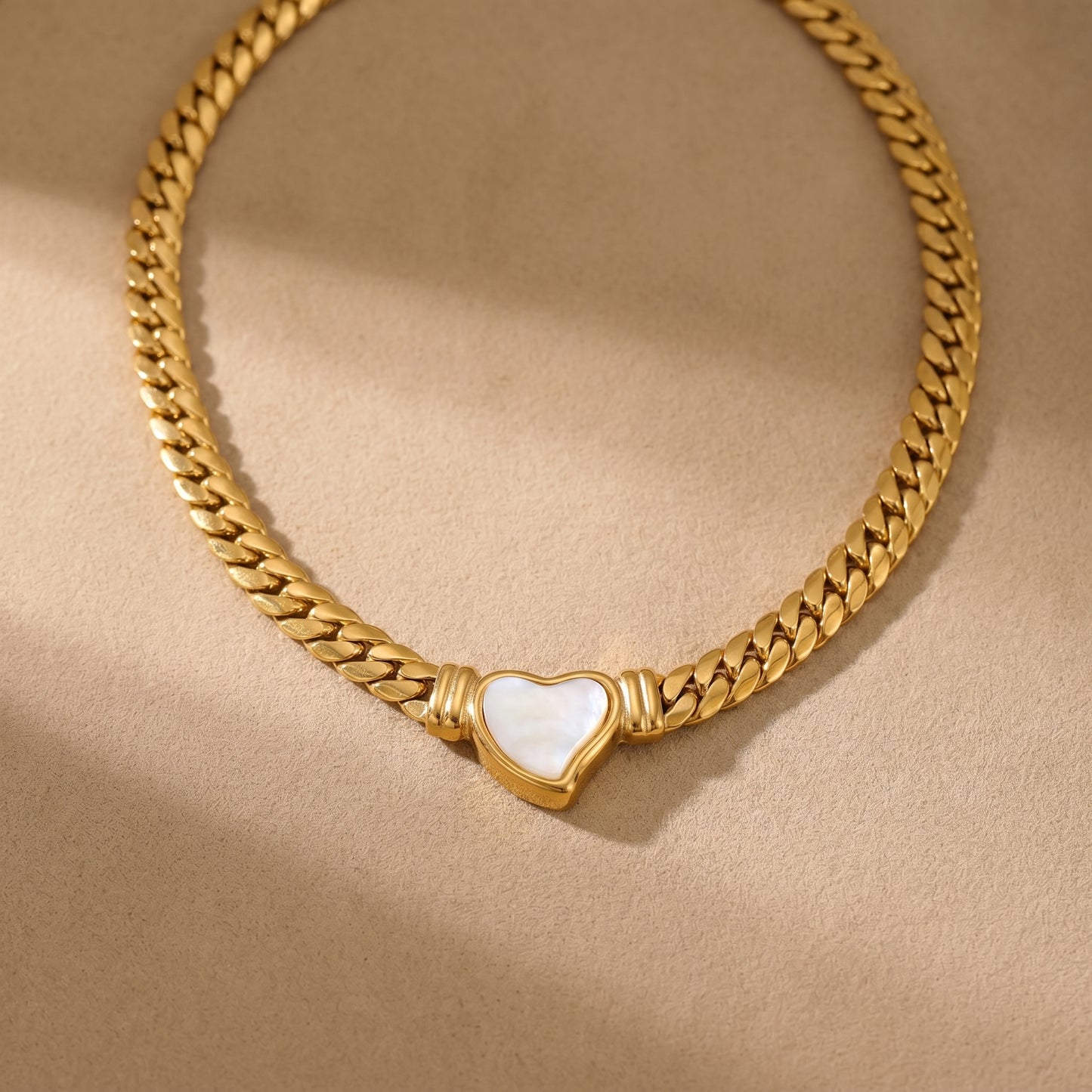 gold snake chain heart pendant necklace on neutral background minimalist luxury jewelry