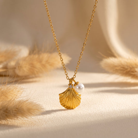 Gold necklace with a shell pendant and pearl on a beige background