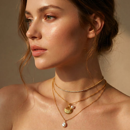 Woman wearing gold necklaces with pendants against a neutral background