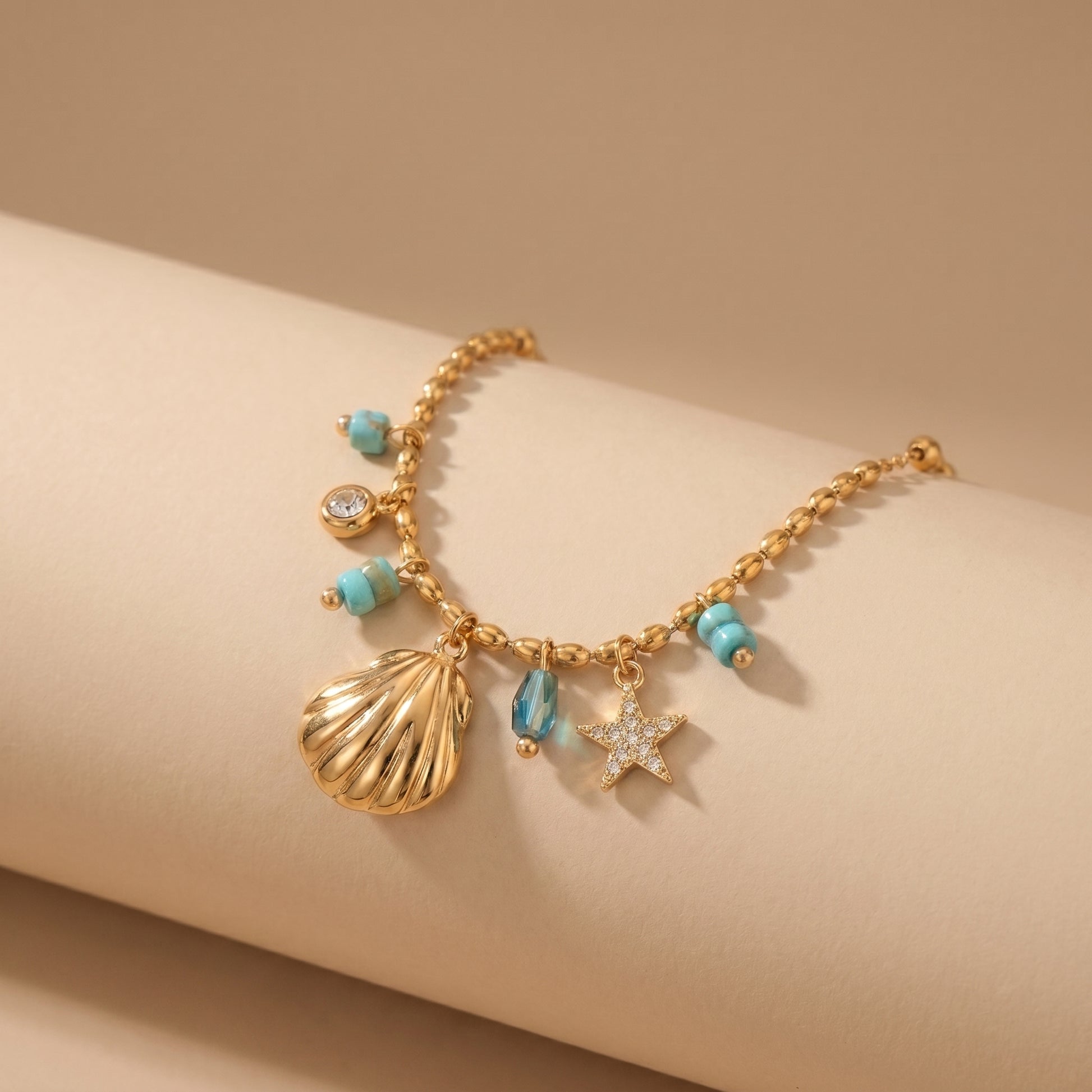 Gold necklace with shell and starfish charms on a beige background