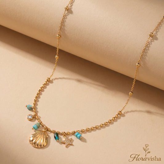 Gold necklace with shell and starfish charms on a beige background, featuring the brand 'Floravisha'.