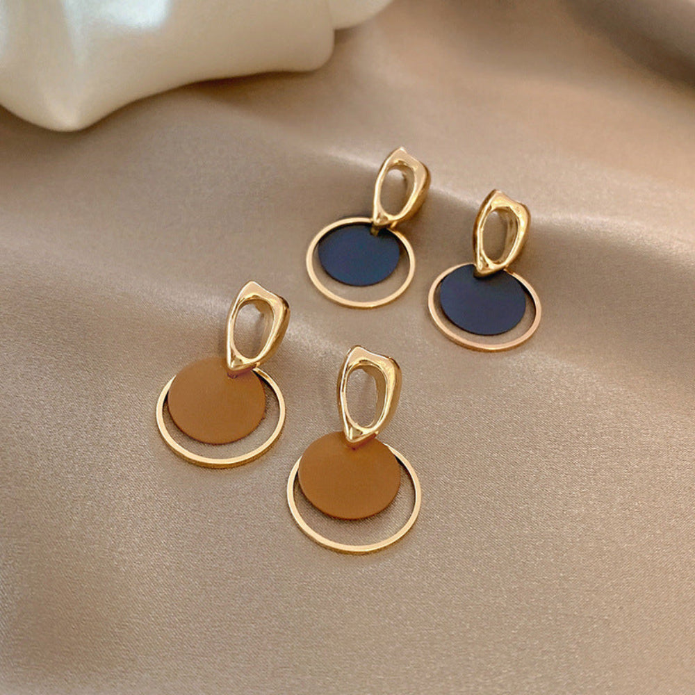 Pair of gold and blue earrings on a beige fabric background.  latest earring models and trending earrings models. new arrivals.