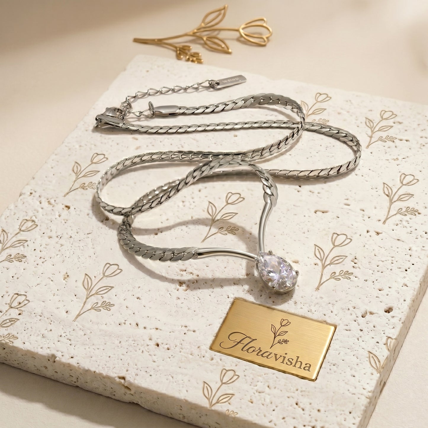 Platinum snake chain necklace with teardrop crystal pendant, minimalist adjustable jewelry for women on textured background