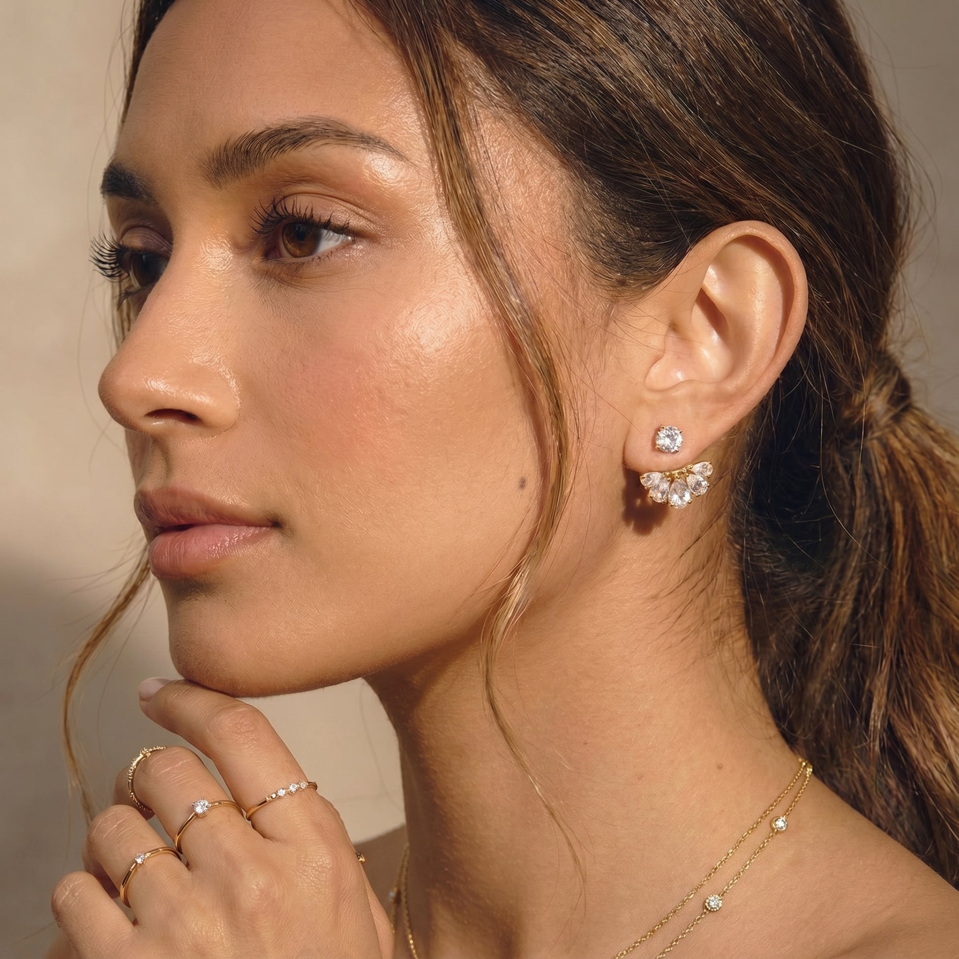 High quality waterproof gold plated 2-in-1 convertible fan earrings featuring a round solitaire stud and an interchangeable fanned crescent of clear crystals worn by a women.
